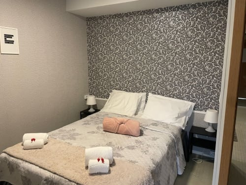 Chambre de la Liber Guest House avec lit double, tête de lit à motifs, oreillers blancs, serviettes de bienvenue et lampes de chevet