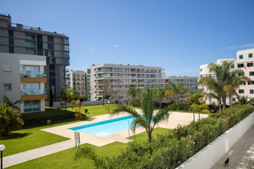 Apartamentos ensolarados com piscina compartilhada, jardim verde e palmeiras em Portugal