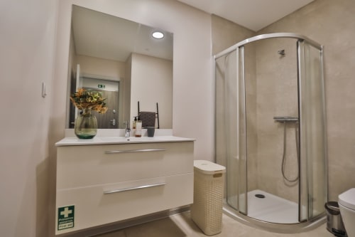 Banheiro moderno no apartamento Rent-A-Key em Portugal com pia branca, espelho, box de duche curvo e vaso sanitário