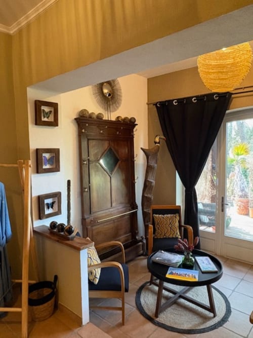 Suite Little Karoo au Lou Paradou Lodge avec murs crème, mobilier en bois, rideaux noirs et accès à une terrasse avec vue sur le jardin