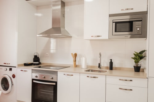 Modern white kitchen with stainless steel appliances and wooden countertops at Alojamientos Estrella Baeza apartment in