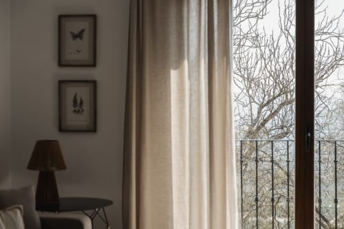 Modern apartment interior with framed nature art, elegant curtains, and bare mountain view through glass door with balcony at