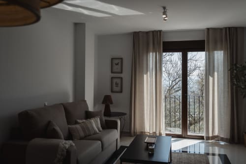 Modern living room in Baeza apartment with mountain views through glass doors, comfortable sofa, and natural lighting