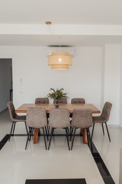 Modern dining room in Baeza apartment with wooden table, upholstered chairs, pendant light, and fresh flowers centerpiece