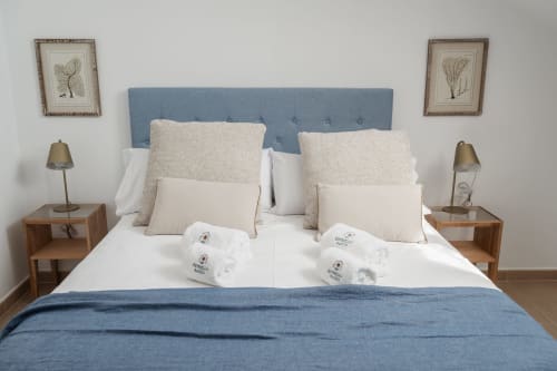 Modern bedroom at Alojamientos Estrella Baeza with blue upholstered headboard, white bedding, and mountain view in Baeza.