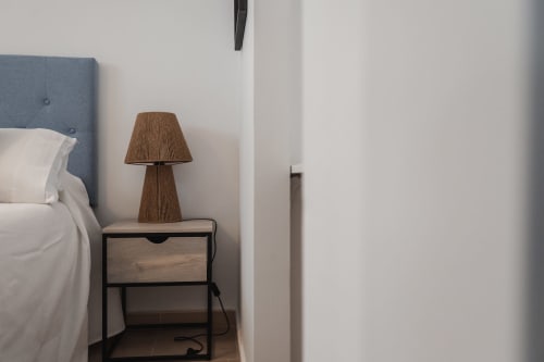 Modern bedroom at Alojamientos Estrella Baeza with blue headboard, nightstand, woven lamp, and white linens in Baeza