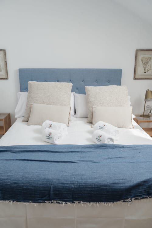 Modern bedroom at Alojamientos Estrella Baeza with blue upholstered headboard, white bedding, and neutral pillows in mountain