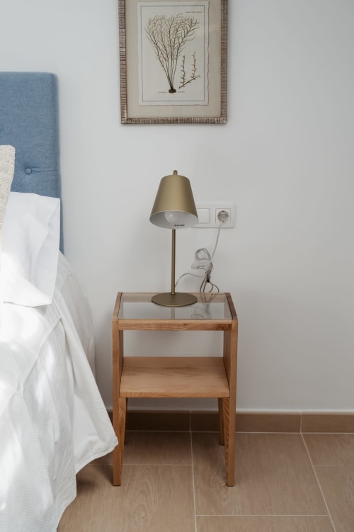 Modern wooden nightstand with brass lamp and glass top in Baeza apartment bedroom