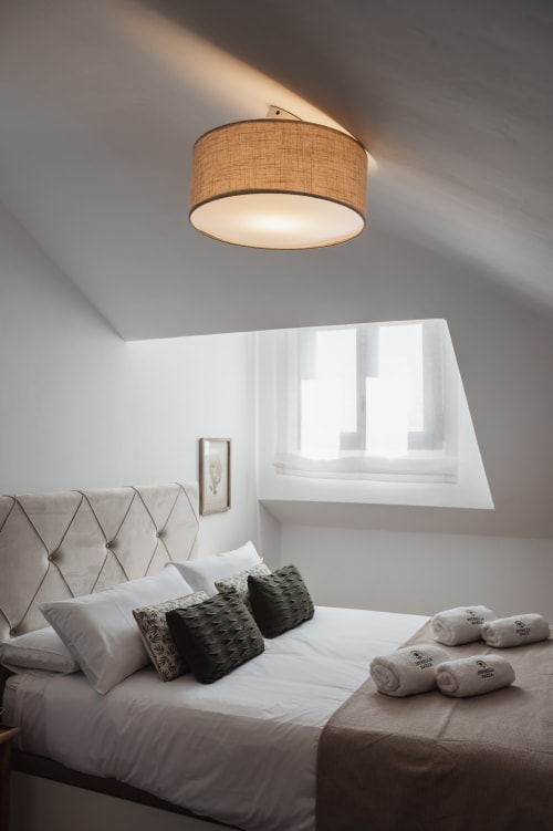 Modern bedroom at Alojamientos Estrella Baeza with tufted headboard, folded towels, and warm ceiling light fixture