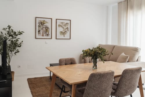 Modern dining area in Baeza apartment with wooden table, upholstered chairs, beige sofa, and mountain view windows
