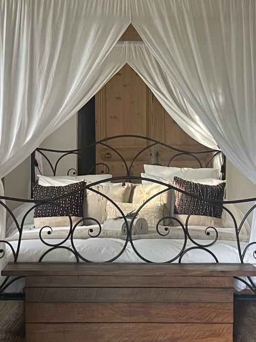 Lit à baldaquin luxueux avec structure en fer forgé, draperies blanches et literie élégante au Lou Paradou Lodge, Grillon