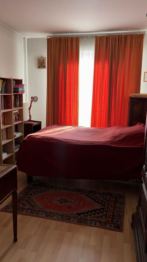 Chambre élégante avec lit bordeaux, rideaux rouges, mobilier en bois et tapis orné à l'hôtel Queen and King Royal à Versailles