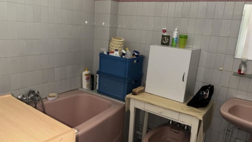 Salle de bains de la Queen And King Royal à Versailles avec baignoire rose, lavabo blanc, rangements bleus et murs carrelés