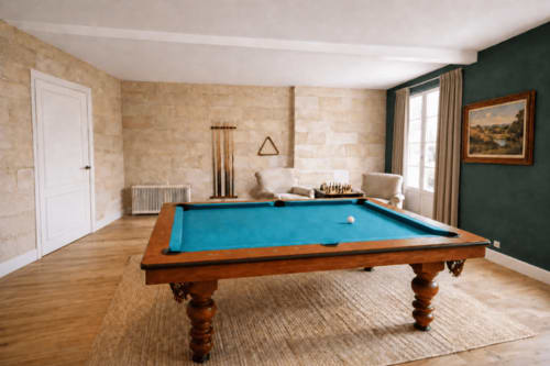 Élégante salle de billard au Château Alto Cormeil à Saint-Émilion avec table de pool en bois, mur d'accent vert et détails en pierre.