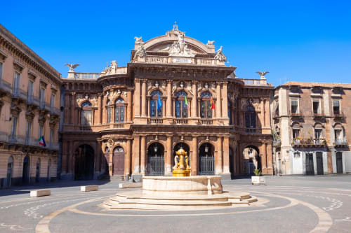 Piazza Università a Catania con edificio barocco ornato e statua dorata, architettura storica siciliana