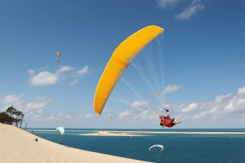 Parapentiste au parachute jaune au-dessus des eaux turquoise près de la plage des Salles-sur-Verdon