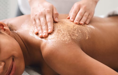 Thérapeute spa appliquant un gommage exfoliant au centre bien-être de l'Hôtel Restaurant Le Verdon