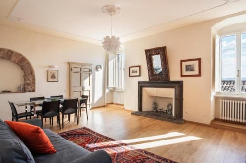 Elegante soggiorno di un appartamento ad Assisi con camino, zona pranzo e muri in terracotta