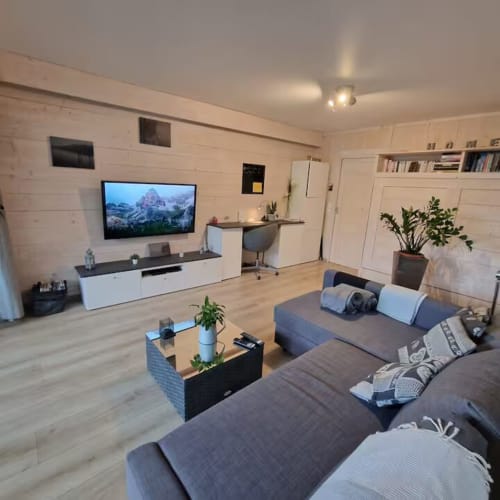 Studio moderne à Zoppas Aix-les-Bains avec canapé gris, TV, placards blancs et parquet