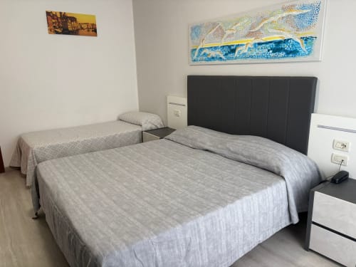Dreibettzimmer im Hotel Panorama in Lido di Jesolo mit zwei Betten, schwarzem Kopfteil und Küstenkunst an den Wänden
