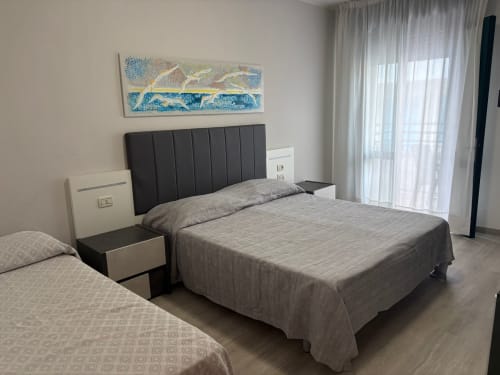 Triple room at Hotel Panorama Lido di Jesolo with dual beds, dark headboard, balcony access, and modern amenities