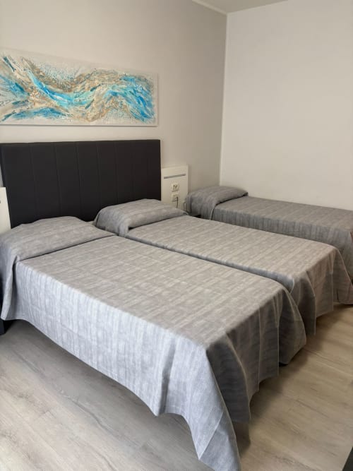 Triple room at Hotel Panorama Lido di Jesolo with two twin beds, black headboard, modern décor, and abstract blue artwork