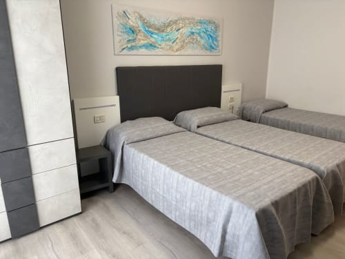 Modern triple room at Hotel Panorama in Lido di Jesolo with three beds, black headboard, and contemporary furnishings