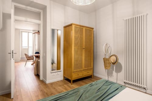 Spacious bedroom with wooden wardrobe, green bedding, white radiator, and access to living area at Dimora Silva Nature Suites
