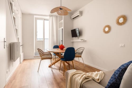 Modern apartment dining area at Dimora Silva Nature Suites with wooden table, blue chairs, and balcony view