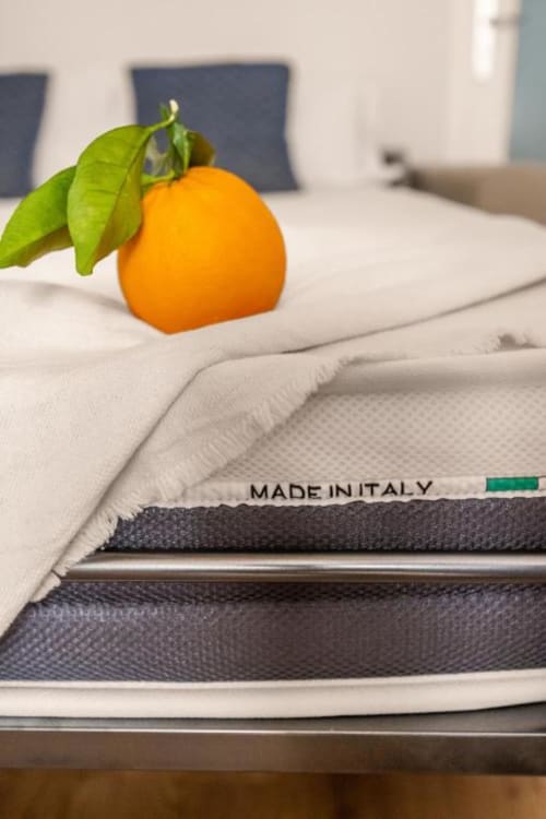 Fresh orange with green leaves on Italian-made mattress at Dimora Silva Nature Suites