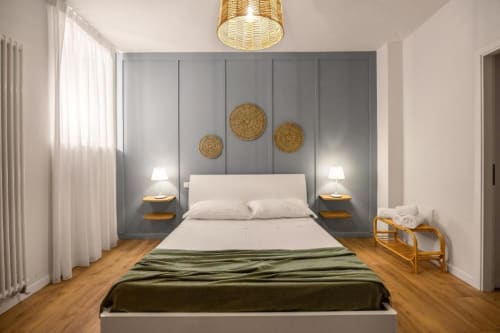 Modern bedroom at Dimora Silva with gray paneled wall, white bed, wooden nightstands, and golden decorative elements in San