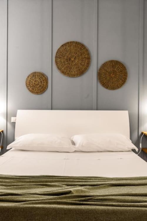 Modern bedroom with white bedding, cream headboard, and three decorative woven baskets on gray paneled wall above bed at
