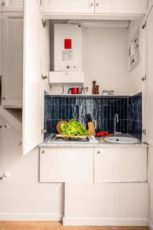Compact kitchenette in San Martino delle Scale apartment with stovetop, fresh vegetables, and dark tile backsplash