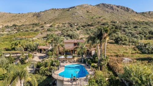 Dimora Silva Nature Suites villa with blue swimming pool surrounded by palm trees and Sicilian hills near San Martino delle