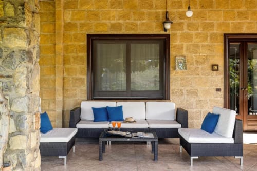 Outdoor patio seating area at Dimora Silva Nature Suites villa with wicker furniture, blue cushions, and stone walls