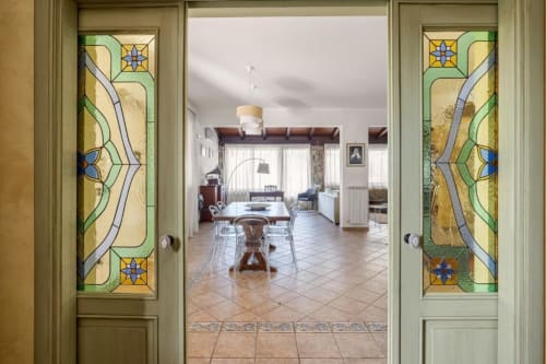 Elegant villa entryway at Dimora Silva with stained glass doors opening to spacious living area with dining table and ocean