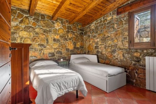 Twin beds in rustic stone villa bedroom at Dimora Silva Nature Suites, San Martino delle Scale with wooden beams and