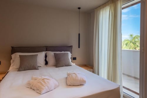 Camera da letto moderna di villa con vista oceano a Dimora Silva Nature Suites, con biancheria bianca e balcone affacciato sul mare
