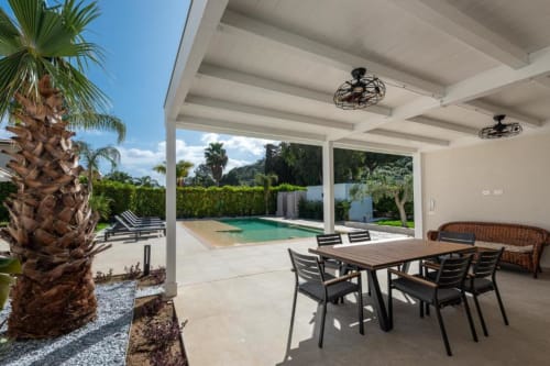 Patio della villa moderna con zona pranzo, piscina privata, palme e vista sul mare a Dimora Silva Nature Suites, Sicilia