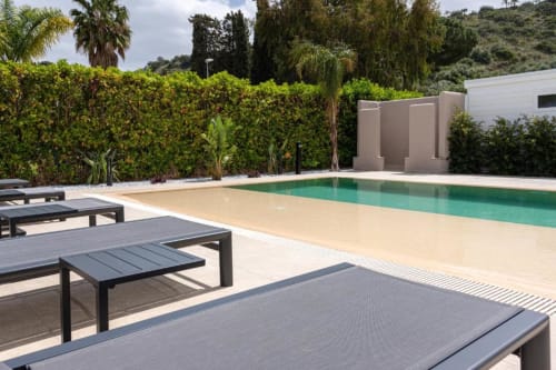 Area piscina della villa moderna con acqua turchese, lettini, siepi curate e viste sulle colline a Dimora Silva Nature