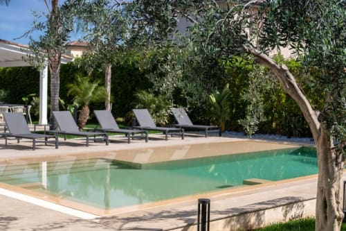 Area piscina della villa di lusso con acqua turchese, lettini prendisole e ulivi a Dimora Silva Nature Suites, San Martino delle