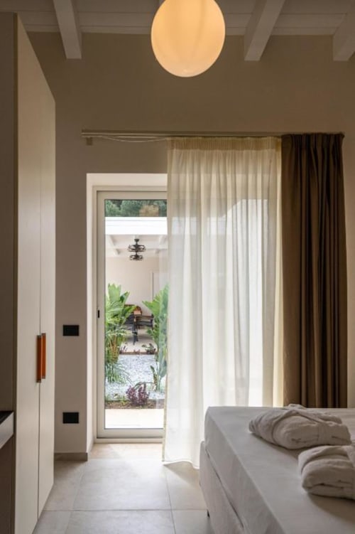 Camera da letto della villa moderna a Dimora Silva Nature Suites con accesso alla vista giardino e arredi contemporanei