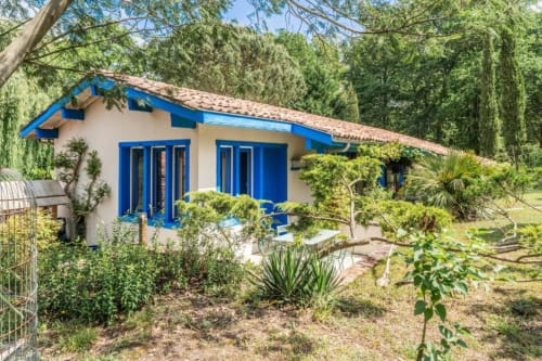 Maison de charme bleu et crème avec vue sur le jardin au Moulin De Lassalle, Linxe, entourée de verdure luxuriante