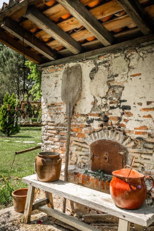 Cuisine extérieure rustique au Moulin De Lassalle avec pots en terre cuite et mur de brique vieilli sous des poutres en bois