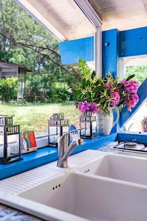 Cuisine moderne aux accents bleus, évier blanc et fleurs roses avec vue sur le jardin du Moulin De Lassalle, Linxe