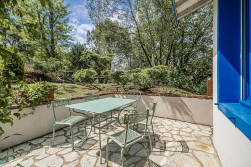 Espace de restauration en terrasse au Moulin De Lassalle avec table, chaises et vue sur le jardin parmi les arbres à Linxe, France