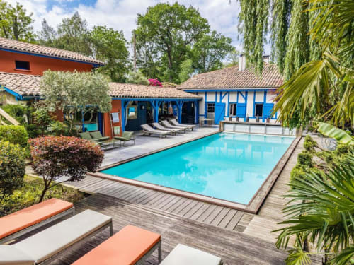 Le Moulin De Lassalle : piscine turquoise, chaises longues, bâtiments bleus et jardins luxuriants à Linxe