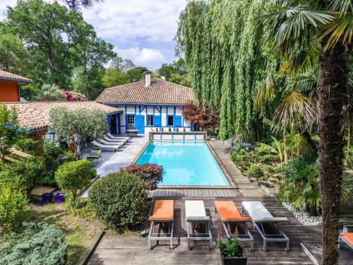 Espace piscine de luxe du Moulin de Lassalle avec maison bleue, transats et palmiers à Linxe, France
