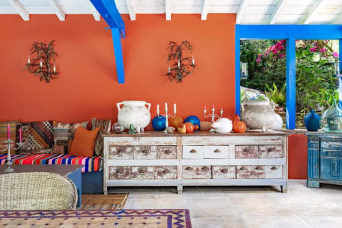 Chambre colorée au Moulin de Lassalle avec murs orange vif, accents bleus et commode rustique peinte à la chaux