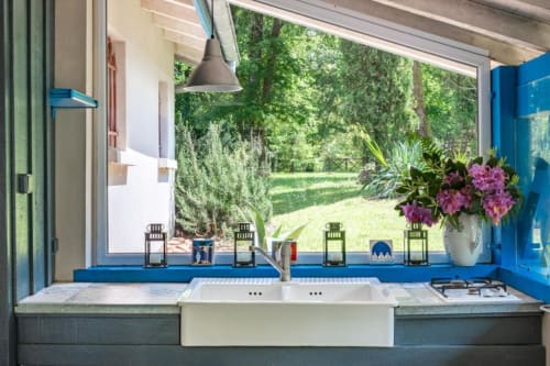 Cuisine moderne avec double évier, touches bleues et vue sur le jardin à l'hôtel Le Moulin De Lassalle à Linxe